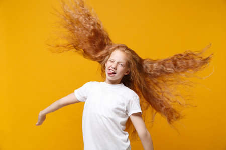 Funny little ginger kid girl 12-13 years old in white t-shirt isolated on yellow background in...