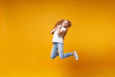 Pretty little ginger kid girl 12-13 years old in white t-shirt isolated on yellow background...