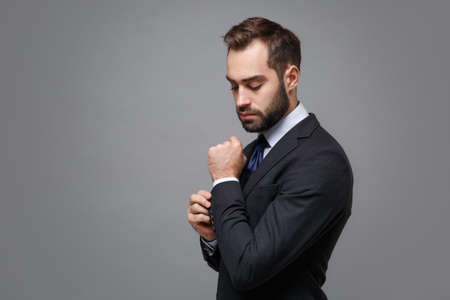 Side view of young business man in classic black suit shirt tie posing isolated on grey background....