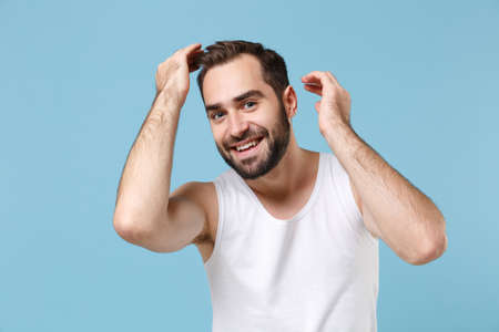 Close up bearded young man 20s years old examining his hair in white shirt isolated on blue pastel wall background studio portrait. Skin care healthcare cosmetic procedures concept. Mock up copy spaceの写真素材