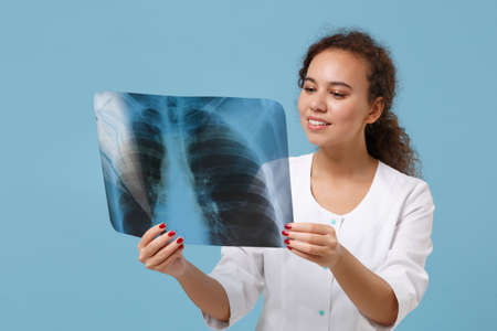 Smiling african american doctor woman in white medical gown hold X-ray of lungs, fluorography,...
