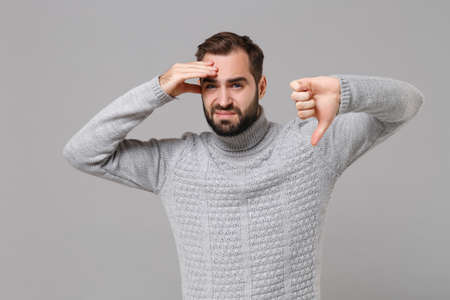 Young bearded man in gray sweater posing isolated on grey wall background. Healthy lifestyle, ill...