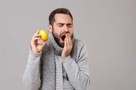 Young man in gray sweater, scarf posing isolated on grey background in studio. Healthy lifestyle,...