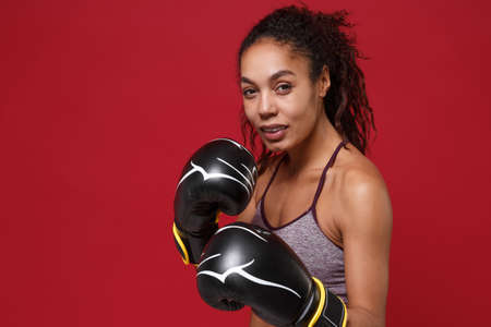 Smiling young african american sports fitness boxer woman in sportswear posing working out isolated...