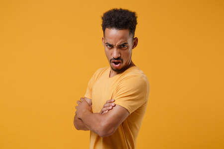 Irritated young african american guy in casual t-shirt posing isolated on yellow orange background...