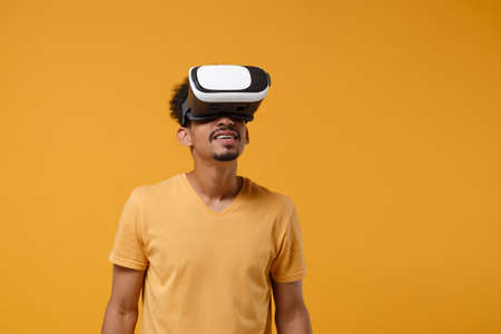 Excited young african american guy in casual t-shirt posing isolated on yellow orange background...
