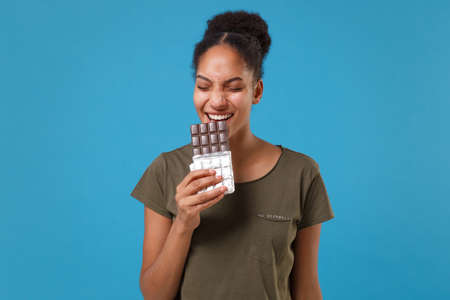 Funny young african american woman girl in casual t-shirt posing isolated on bright blue background...