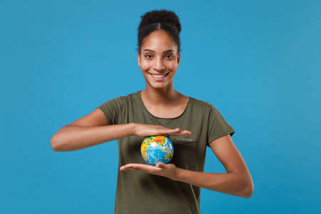 Smiling young african american woman girl in casual t-shirt posing isolated on bright blue...