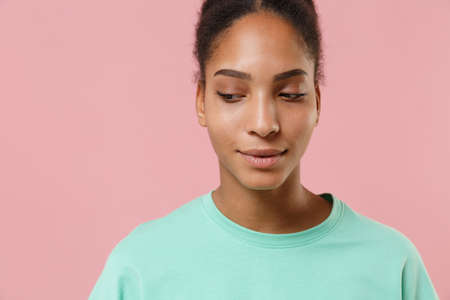 Close up of pretty young african american woman girl in green sweatshirt posing isolated on pastel...