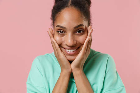 Close up of charming young african american woman girl in green sweatshirt posing isolated on pastel...