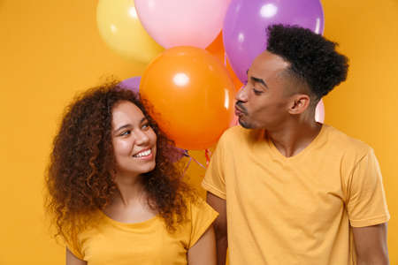 Pretty friends couple african american guy girl in casual clothes isolated on yellow background....