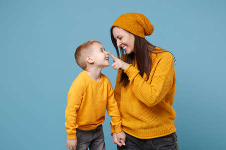 Woman in yellow clothes have fun posing with cute child baby boy 4-5 years old. Mommy little kid son isolated on blue background studio portrait. Mothers Day love family parenthood childhood concept.の写真素材