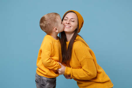 Woman in yellow clothes have fun posing with cute child baby boy 4-5 years old. Mommy little kid son isolated on blue background studio portrait. Mothers Day love family parenthood childhood concept.の写真素材