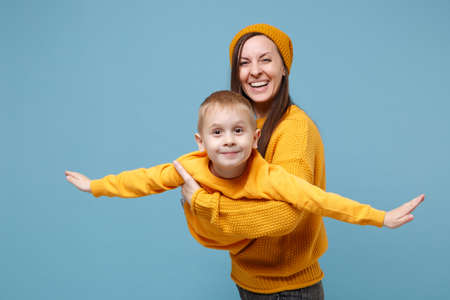 Woman in yellow clothes have fun posing with cute child baby boy 4-5 years old. Mommy little kid son isolated on blue background studio portrait. Mothers Day love family parenthood childhood concept.の写真素材