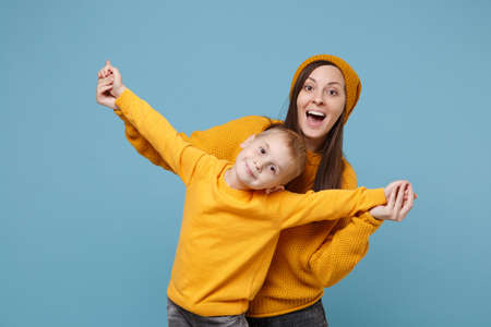 Woman in yellow clothes have fun posing with cute child baby boy 4-5 years old. Mommy little kid son isolated on blue background studio portrait. Mothers Day love family parenthood childhood concept.の写真素材