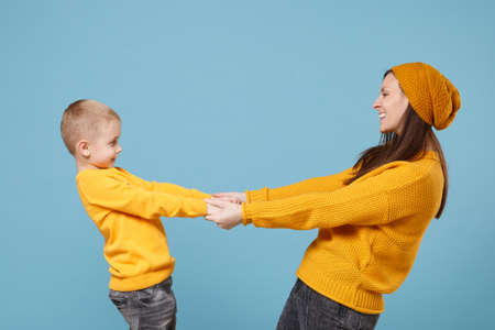 Woman in yellow clothes have fun posing with cute child baby boy 4-5 years old. Mommy little kid son isolated on blue background studio portrait. Mothers Day love family parenthood childhood concept.の写真素材