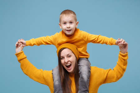 Woman in yellow clothes have fun posing with cute child baby boy 4-5 years old. Mommy little kid son isolated on blue background studio portrait. Mothers Day love family parenthood childhood concept.の写真素材