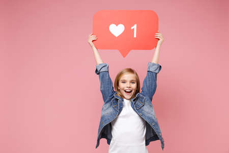 Funny little kid girl 12-13 years old in denim jacket isolated on pastel pink wall background in...