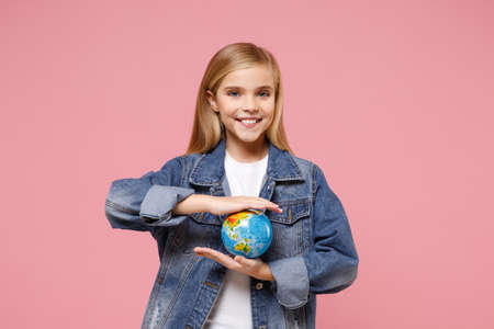 Beautiful little blonde kid girl 12-13 years old in denim jacket posing isolated on pastel pink wall...