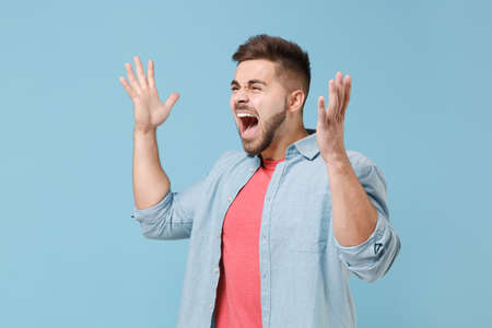 Angry irritated young bearded guy 20s in casual shirt posing isolated on pastel blue background...