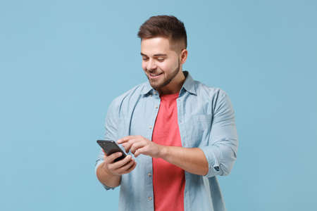 Smiling young bearded guy 20s in casual shirt posing isolated on pastel blue wall background studio...