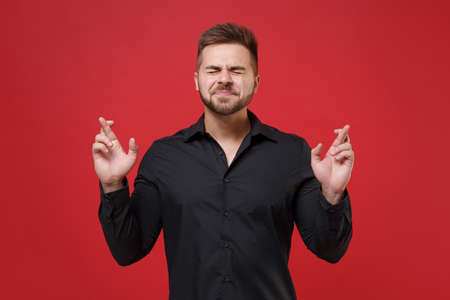 Young bearded guy in classic black shirt posing isolated on red background. People lifestyle...