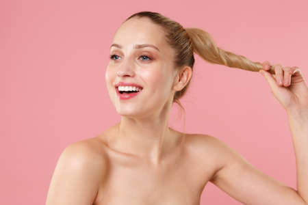 Close up blonde half naked woman 20s perfect skin nude make up blue eyes isolated on pastel pink...