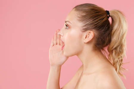 Close up blonde half naked woman 20s perfect skin nude make up blue eyes isolated on pastel pink...