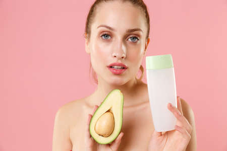 Close up half naked woman 20s perfect skin nude make up blue eyes hold in hand fresh avocado bottle...