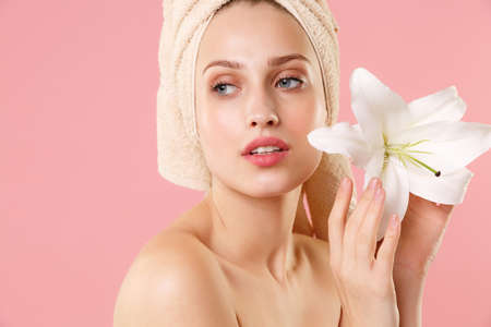Close up blonde half naked woman 20s perfect skin nude make up isolated on pastel pink wall background studio portrait. Skin care healthcare cosmetic procedures concept. Mock up copy space Lily flowerの写真素材