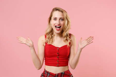 Excited young woman girl in red sexy clothes posing isolated on pastel pink wall background studio...