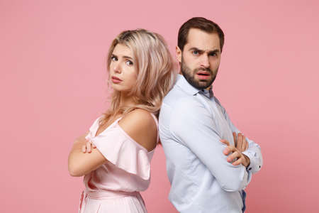 Perplexed young couple two guy girl in party outfit celebrating posing isolated on pastel pink background. People lifestyle Valentines Day Womens Day birthday holiday concept. Holding hands crossed.の写真素材