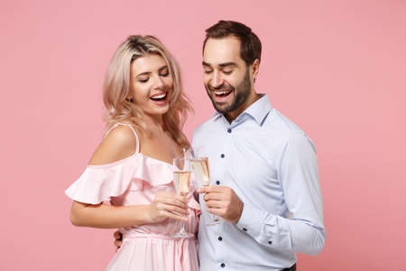 Funny young couple two guy girl in party outfit celebrating posing isolated on pastel pink background. People lifestyle Valentines Day Womens Day birthday holiday concept. Hold glass of champagne.の写真素材