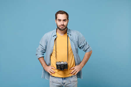 Traveler tourist man in yellow summer casual clothes with photo camera on neck isolated on blue...