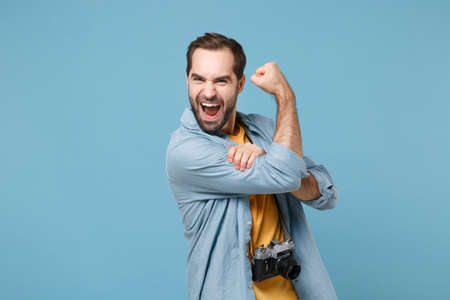 Funny traveler tourist man in yellow summer clothes with photo camera isolated on blue background....