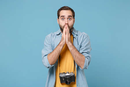 Shocked traveler tourist man in yellow summer clothes with photo camera isolated on blue background....