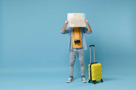 Traveler tourist man in yellow clothes with photo camera, suitcase isolated on blue background. Male...