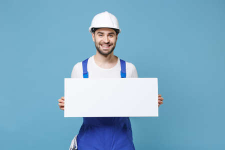 Smiling man in coveralls protective helmet hardhat hold blank sign board with place for text...