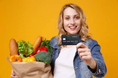 Pretty young woman in denim clothes isolated on orange background. Delivery service from shop or...