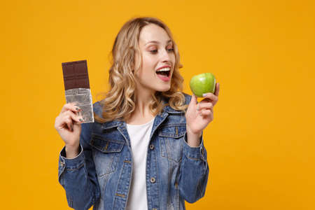 Cheerful young woman in denim clothes isolated on yellow orange background in studio. Proper...