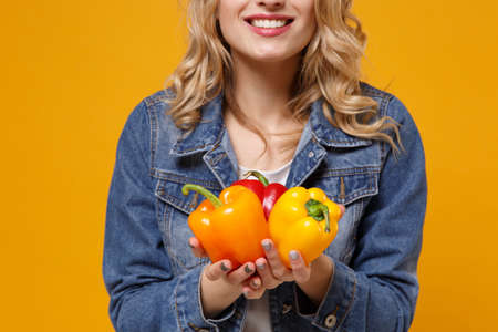 Cropped image of young woman in denim clothes isolated on yellow orange background. Proper nutrition...