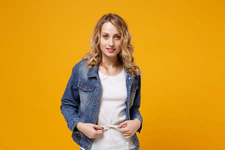 Smiling young woman in denim clothes isolated on yellow orange wall background. Proper nutrition...