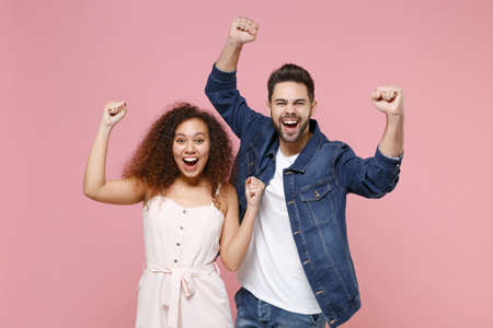 Excited happy young couple two friends european guy african american girl in casual clothes posing...