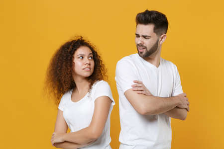 Confused young couple friends european guy african american girl in white t-shirts isolated on...