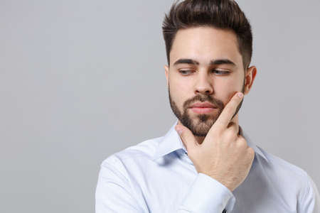 Young unshaven business man in light shirt posing isolated on grey background in studio. Achievement...