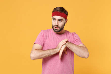 Young bearded fitness sporty guy 20s sportsman in headband t-shirt spend weekend in home gym isolated on yellow background. Workout sport motivation concept. Doing stretching exercising for hands.の写真素材