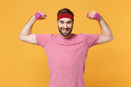 Cheerful bearded fitness sporty guy 20s sportsman in headband t-shirt spend weekend in home gym...