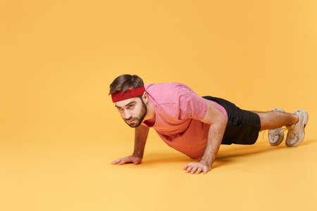 Young bearded fitness sporty guy sportsman in headband t-shirt spend weekend in home gym isolated on...