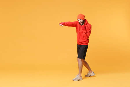 Side view screaming bearded fitness sporty guy boxer sportsman in hat, hoodie, shorts in home gym...
