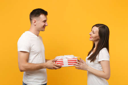 Joyful couple in white t-shirts posing isolated on yellow orange background. Valentines Day, Womens...